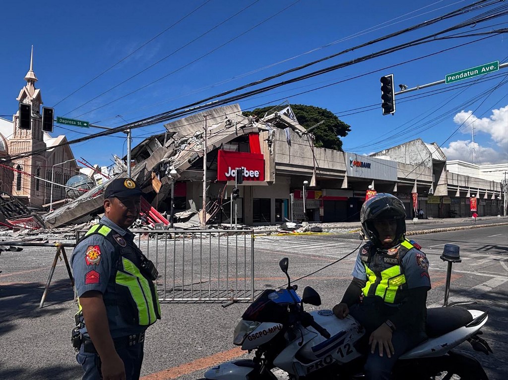 菲律宾桑托斯将军市周一发生7.8级地震后,警方聚集在倒塌的Jollibee快餐店前。(图取自法新社) 菲律宾桑托斯将军市周一发生7.8级地震后,警方聚集在倒塌的Jollibee快餐店前。(图取自法新社)