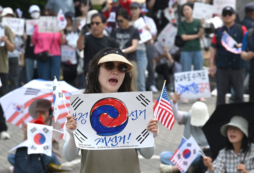 6月10日，韩国示威者在首尔一处计票中心外挥舞国旗，要求因选票短缺而重新举行地方选举。（图取自法新社）