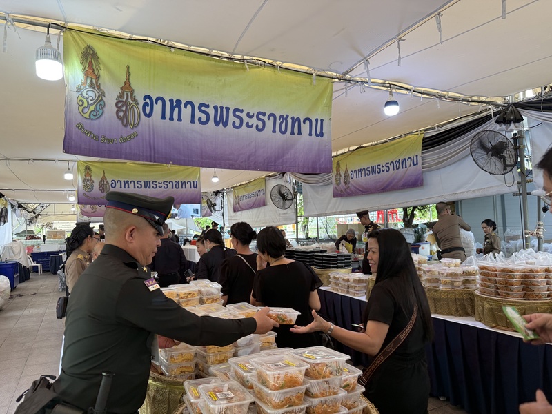 泰国大皇宫外设置御赐餐食发放区，提供免费食物与饮水供民众取用。（图取自中新社）