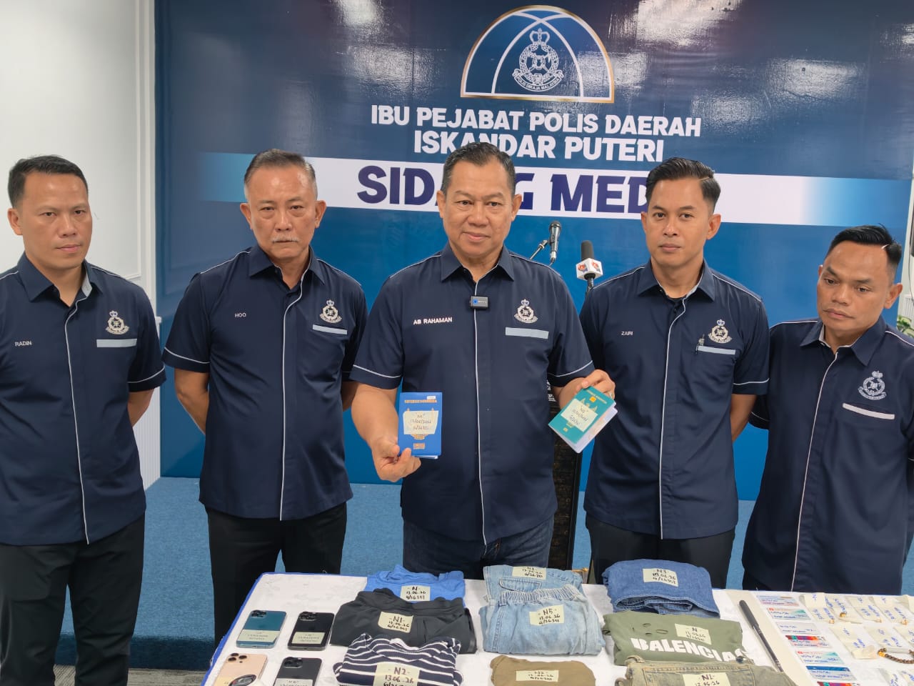 拉哈曼（左3）展示其中一名嫌犯保管的两名女佣护照，左起为拉丁、何泉发、莫哈末再利和拉勿。