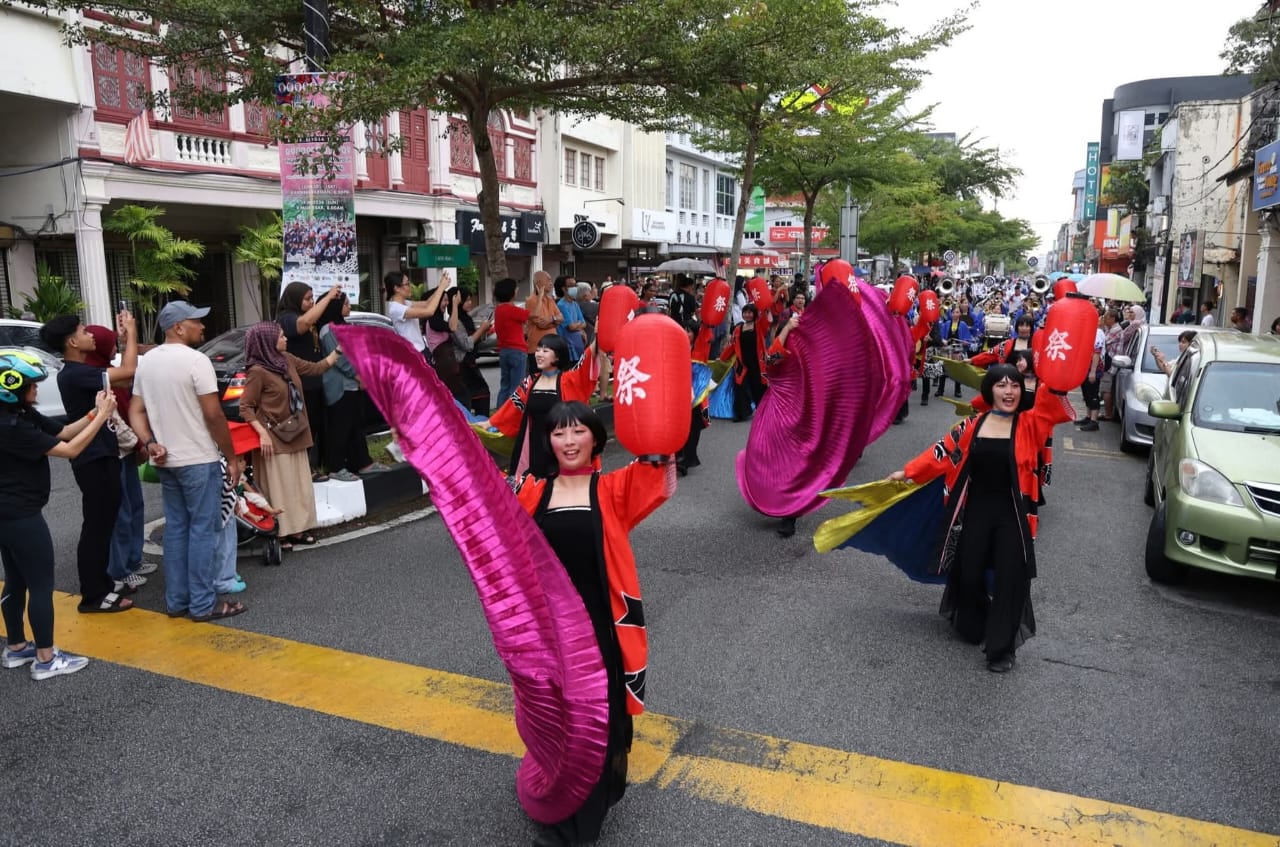 行进管乐队伍从太平历史广场浩荡出发，沿著敏路及古打路巡游，吸引民众站满街道两旁，举起手机记录精彩瞬间，掌声与欢呼声此起彼落。